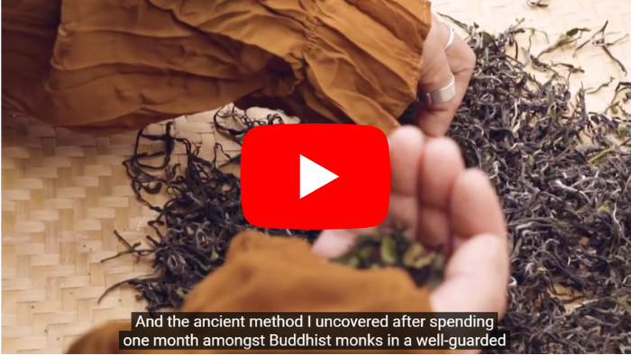 A person holding their chest in discomfort reflecting high blood pressure pain the person is in a calm home environment with soft lighting The image has a small circular inset showing a simple breathing exercise illustrated visually The main image has a centered red YouTube style play button with white play icon, no text no logo